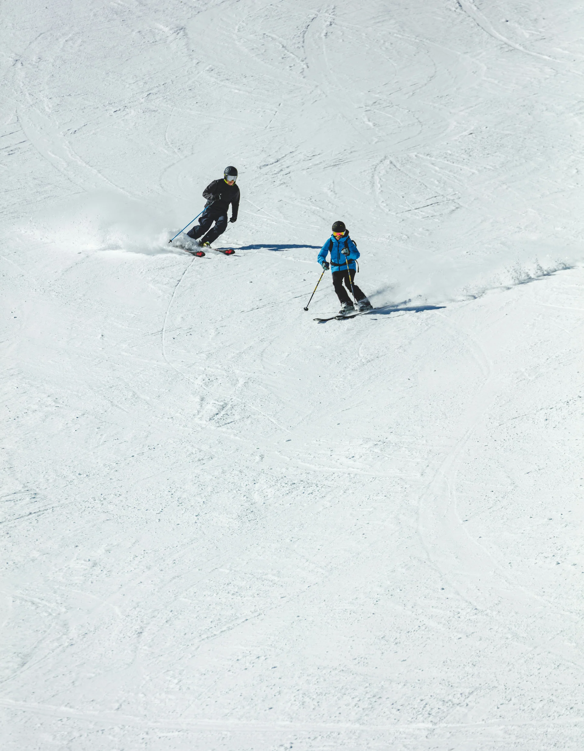 Familienferien in Zermatt - Resort La Ginabelle Zermatt Zwei Skifahrer fahren auf schneebedeckter Piste bei Sonnenschein