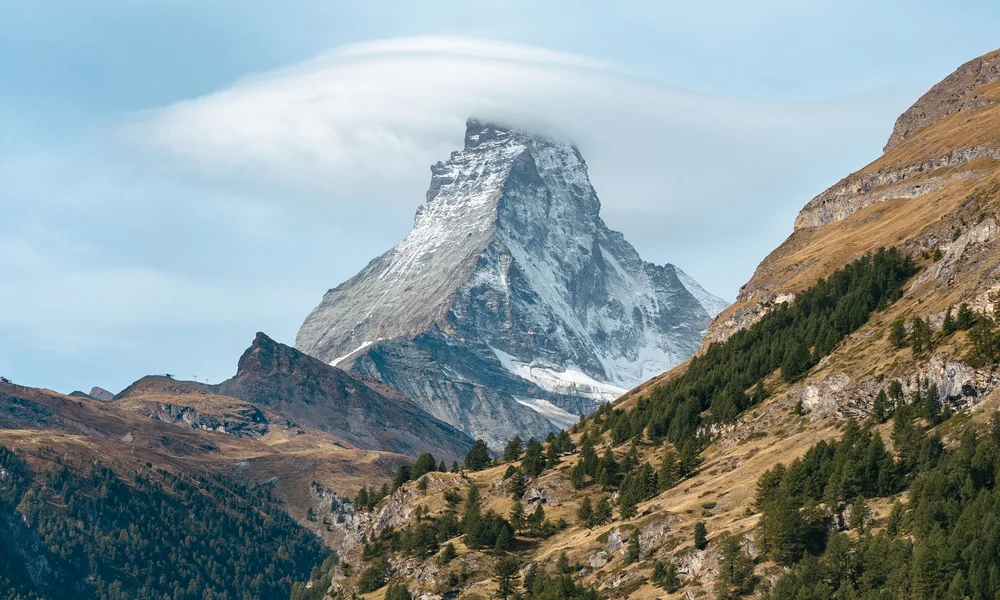 Sommet de montagne enneigé avec nuage au-dessus d'un village en vallée