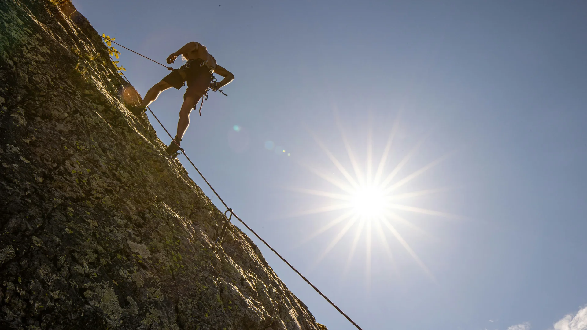 Klettern & Bergsteigen Person klettert an steiler Felswand bei Sonnenschein