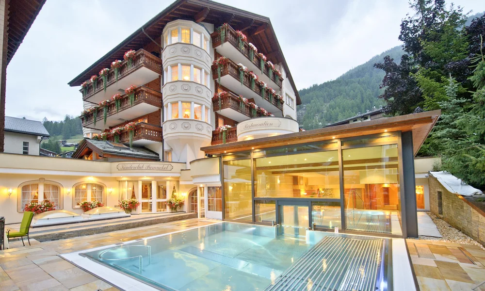 Beheizter Aussenpool mit Hotel im Hintergrund im Sommer am Abend.