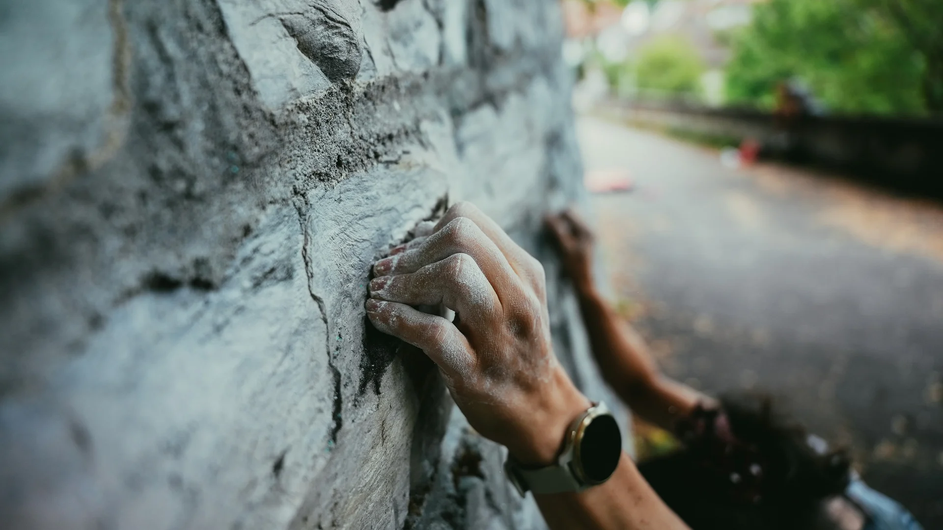 Klettern & Bergsteigen Kletterer hält sich an Felsen bei Outdoor-Kletterwand fest