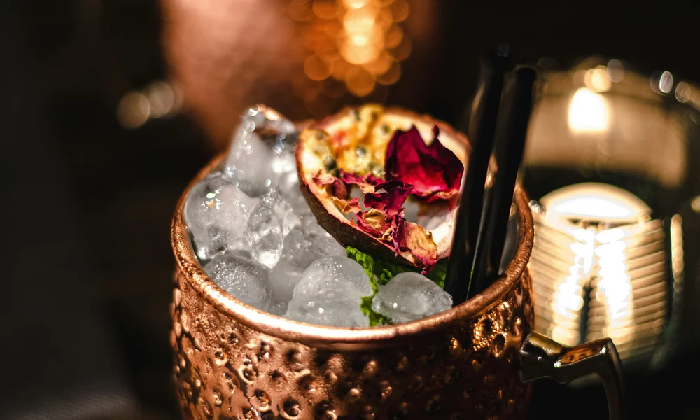 Copper mug with ice, cocktail, and garnish of leaves and fruit slice