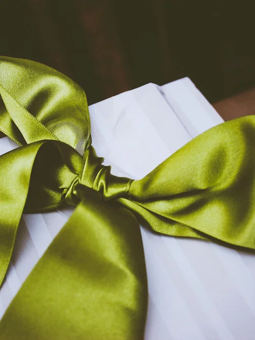 Nahaufnahme einer weißen Geschenkbox mit grünem Satinschleifenband
