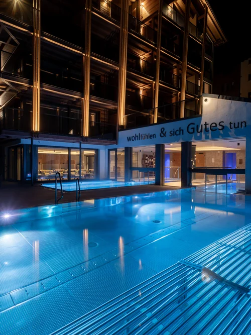 Beleuchtetes Hotel mit Infinitypool in der Nacht.