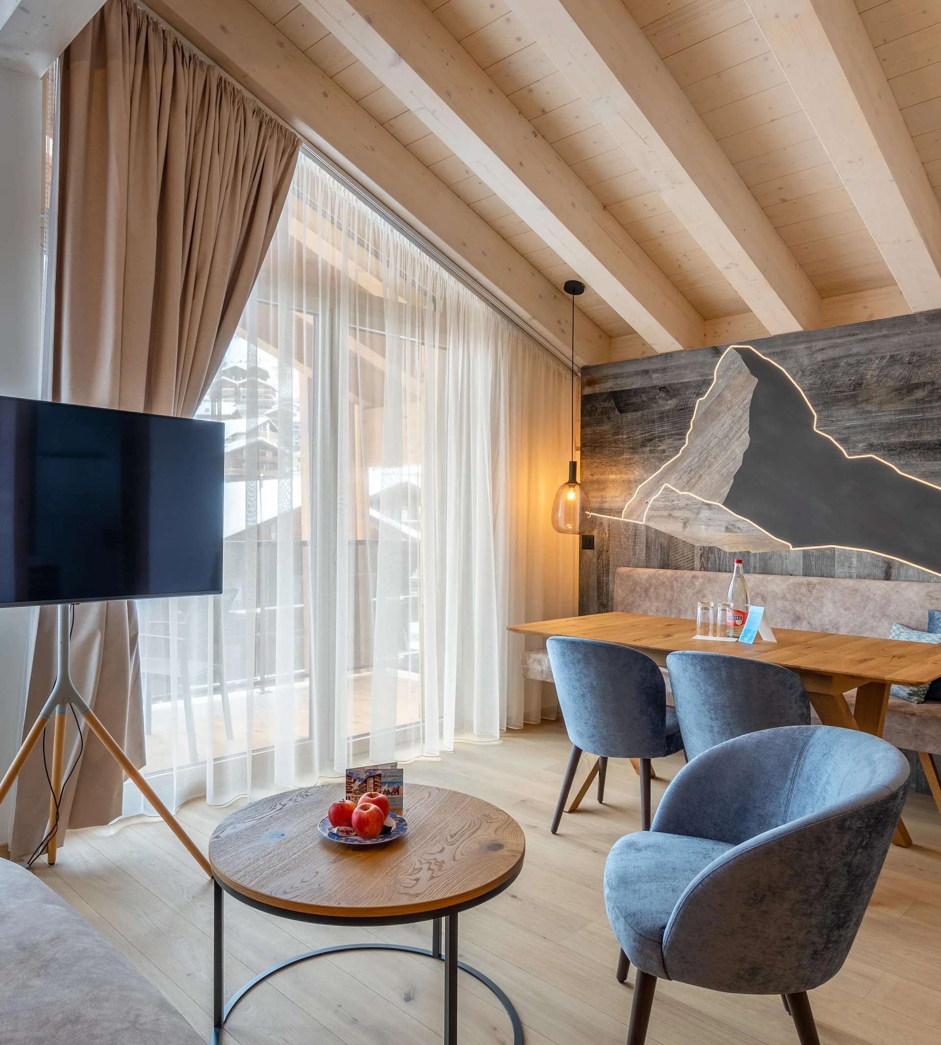Your 4*S Wellnessresort in Zermatt - Resort La Ginabelle Zermatt Living area of the apartment with TV and illuminated Matterhorn made of wood