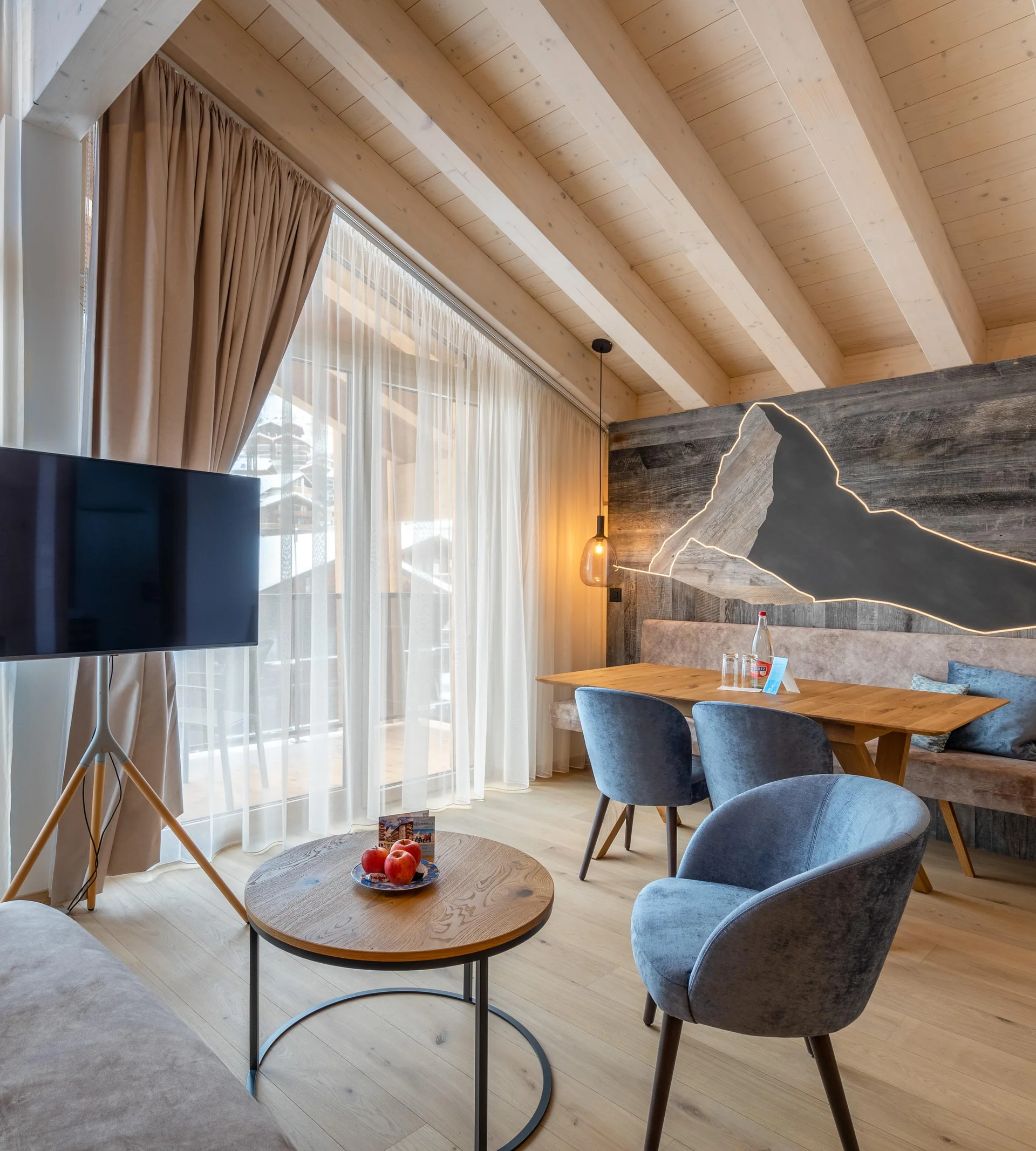 Wohnbereich des Appartements mit TV und beleuchtetem Matterhorn aus Holz