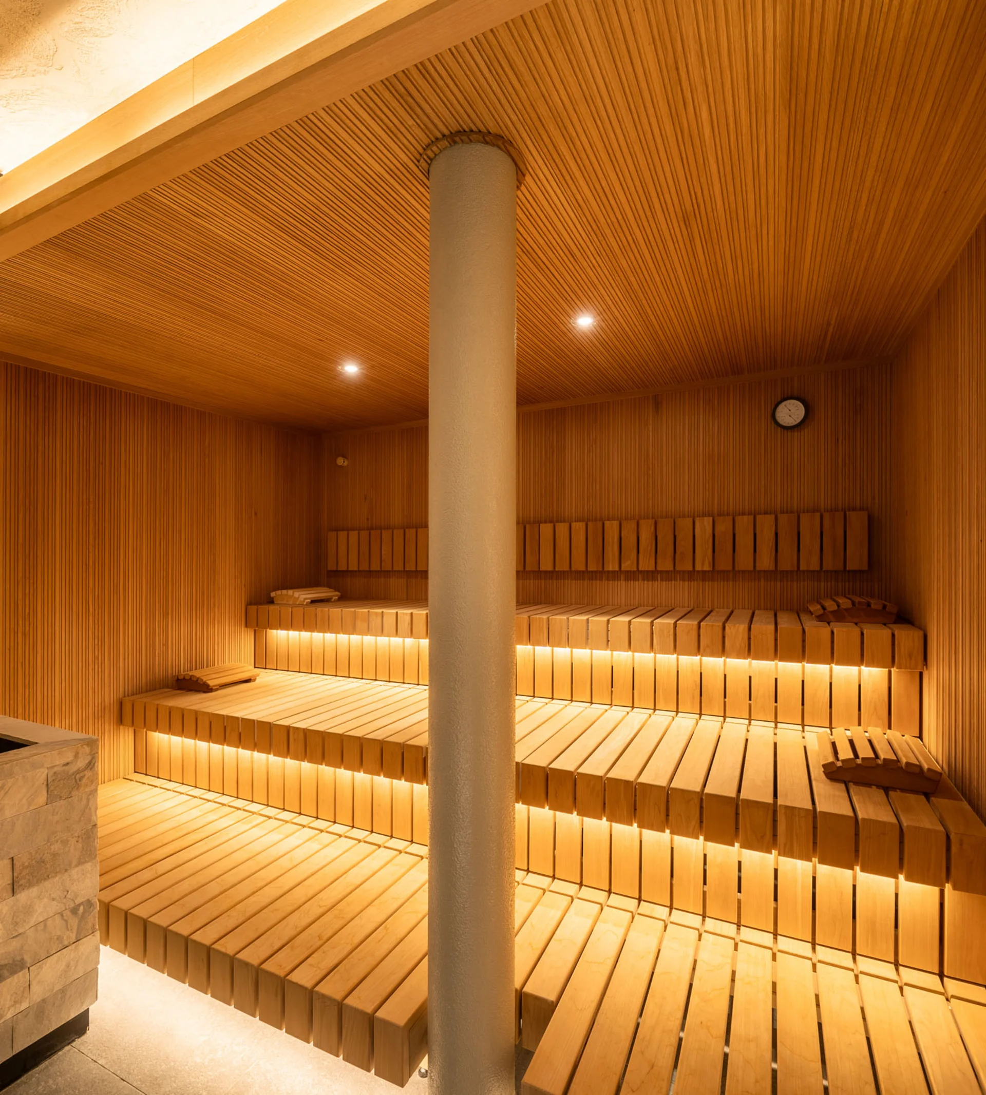 Moderner Holzsauna mit beleuchteten Bänken und Steinofen