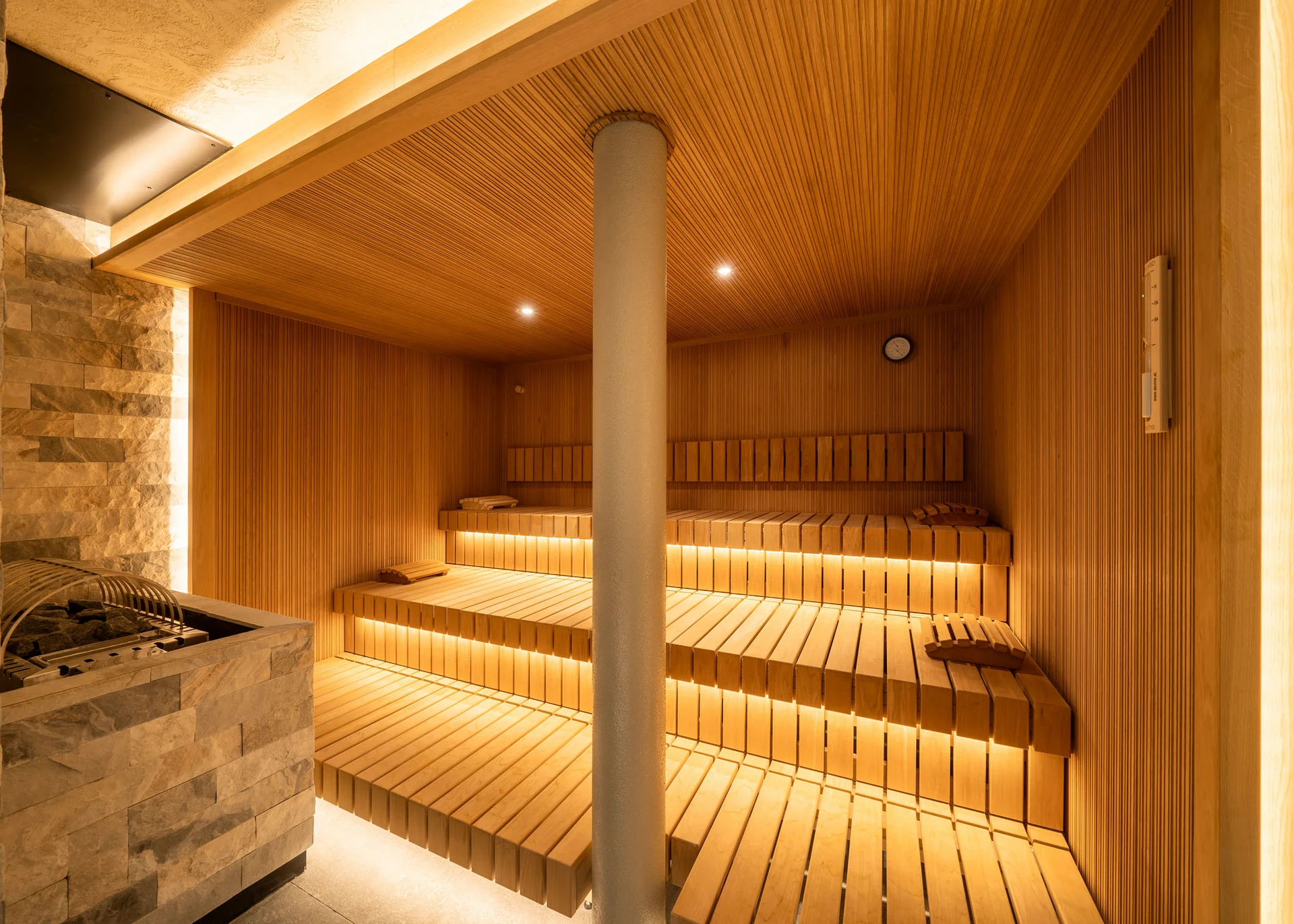 Moderner Holzsauna mit beleuchteten Bänken und Steinofen