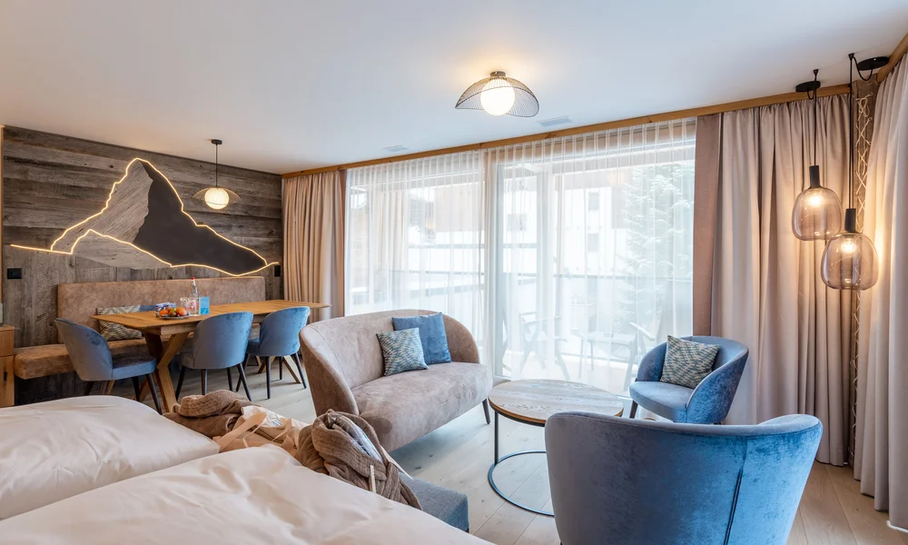 Appartements à Zermatt - Resort La Ginabelle Zermatt Chambre d'hôtel moderne avec coin salon et grande fenêtre avec rideaux