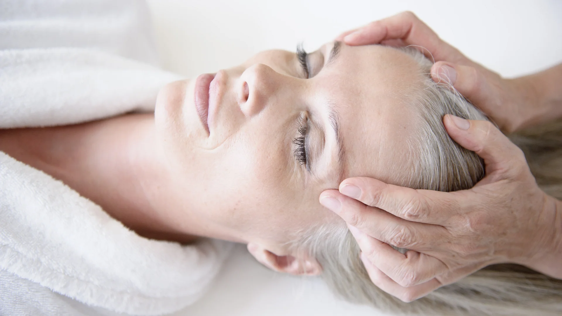Eine entspannte Frau erhält eine Kopfmassage.
