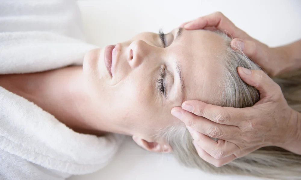 Eine entspannte Frau erhält eine Kopfmassage.