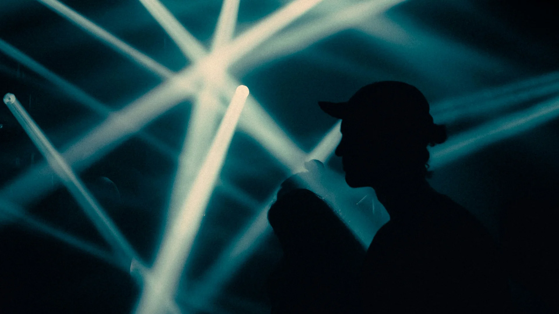 Silhouette of a person against bright crossing light beams in a dark space