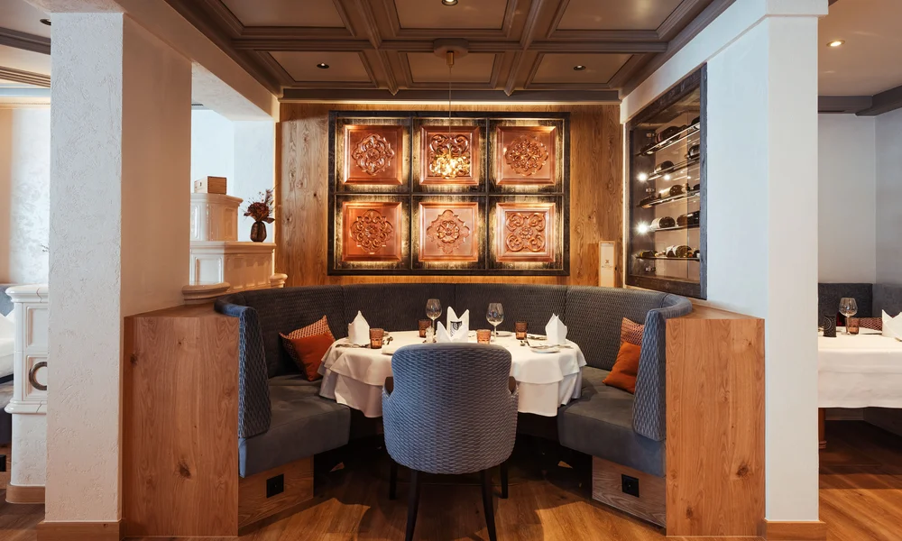 Restaurant La Ginabelle - Resort La Ginabelle Zermatt Gedeckter Tisch in edlem Restaurant mit beleuchteter Wandbekleidung.