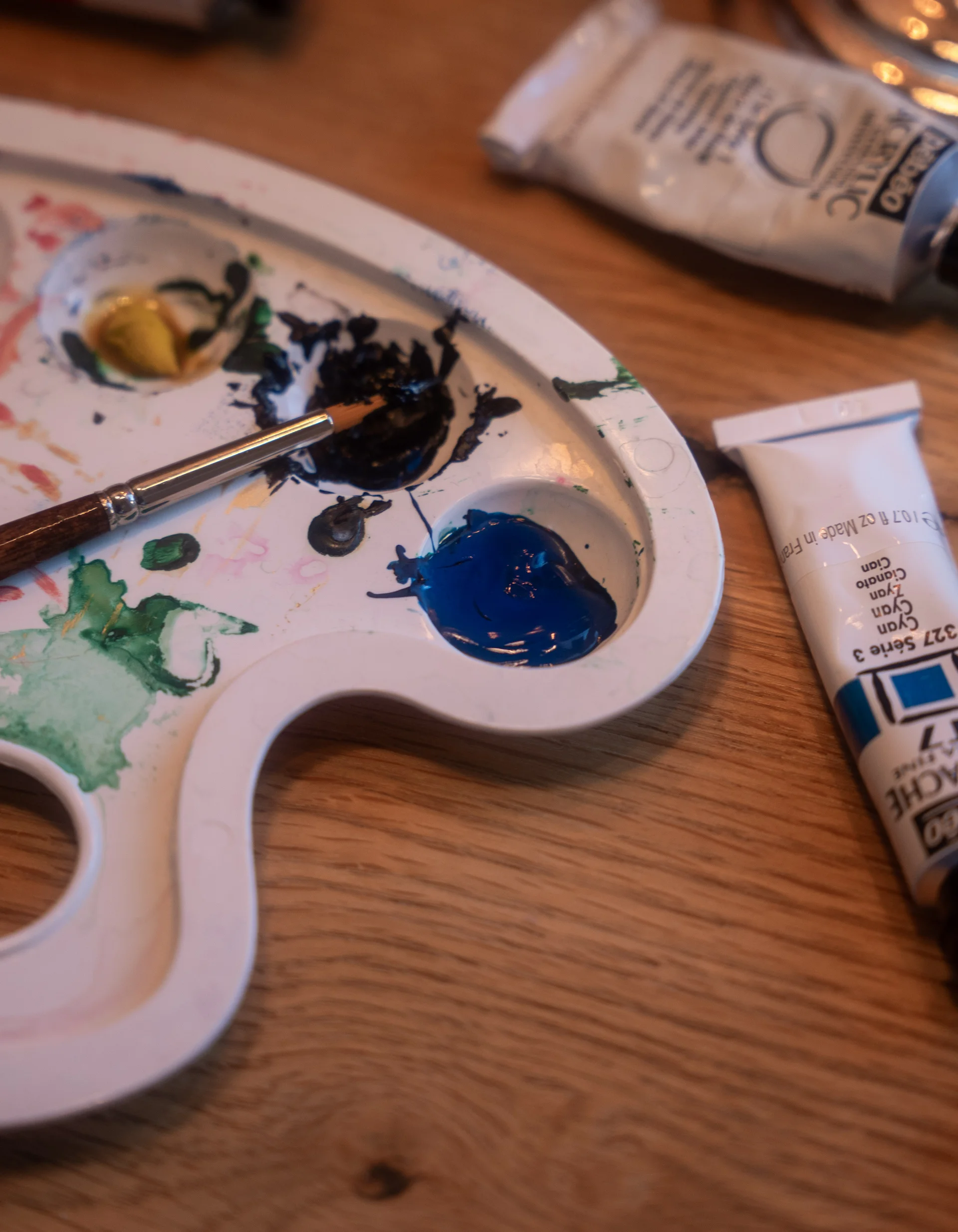 acotar Malfarbenpalette und Tuben mit Acrylfarben auf Holztisch