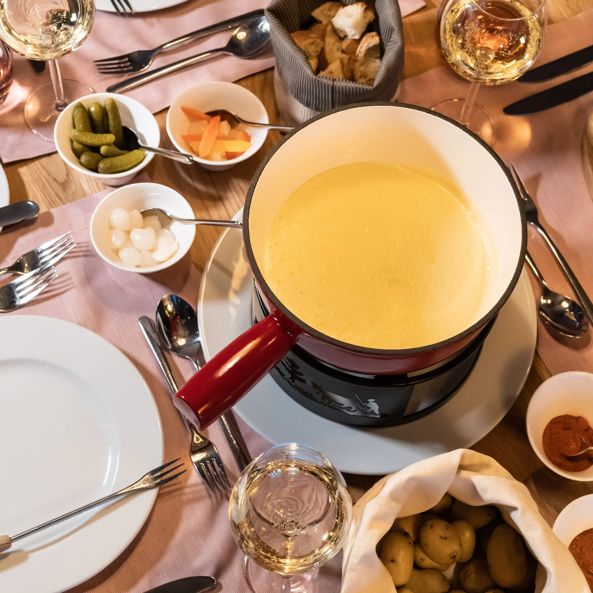 Käsefondue im Topf auf einem gedeckten Tisch.