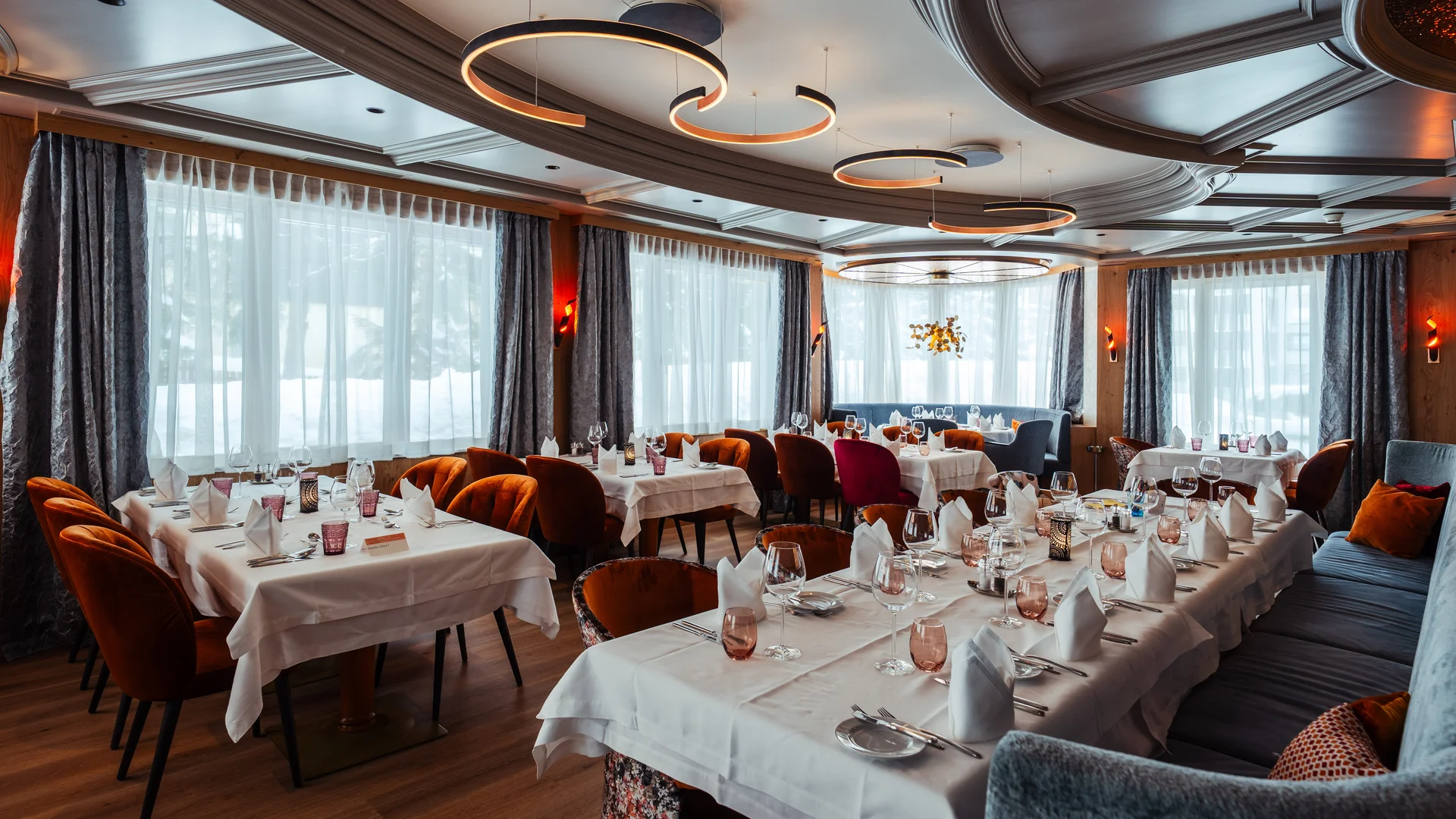 Eingedecktes Restaurant mit unterschiedlichen Tischen und grossen Fenstern.