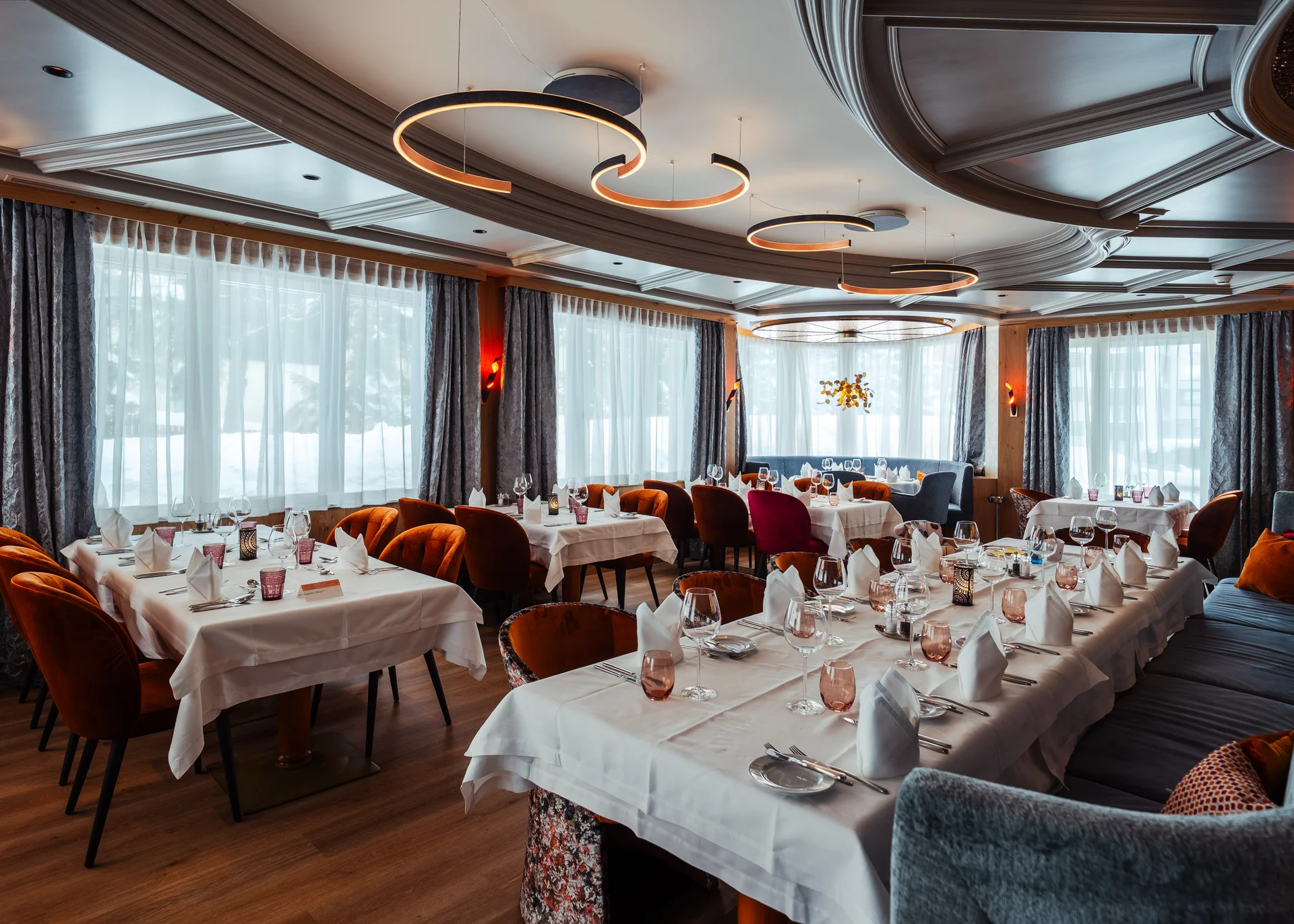 Eingedecktes Restaurant mit unterschiedlichen Tischen und grossen Fenstern.