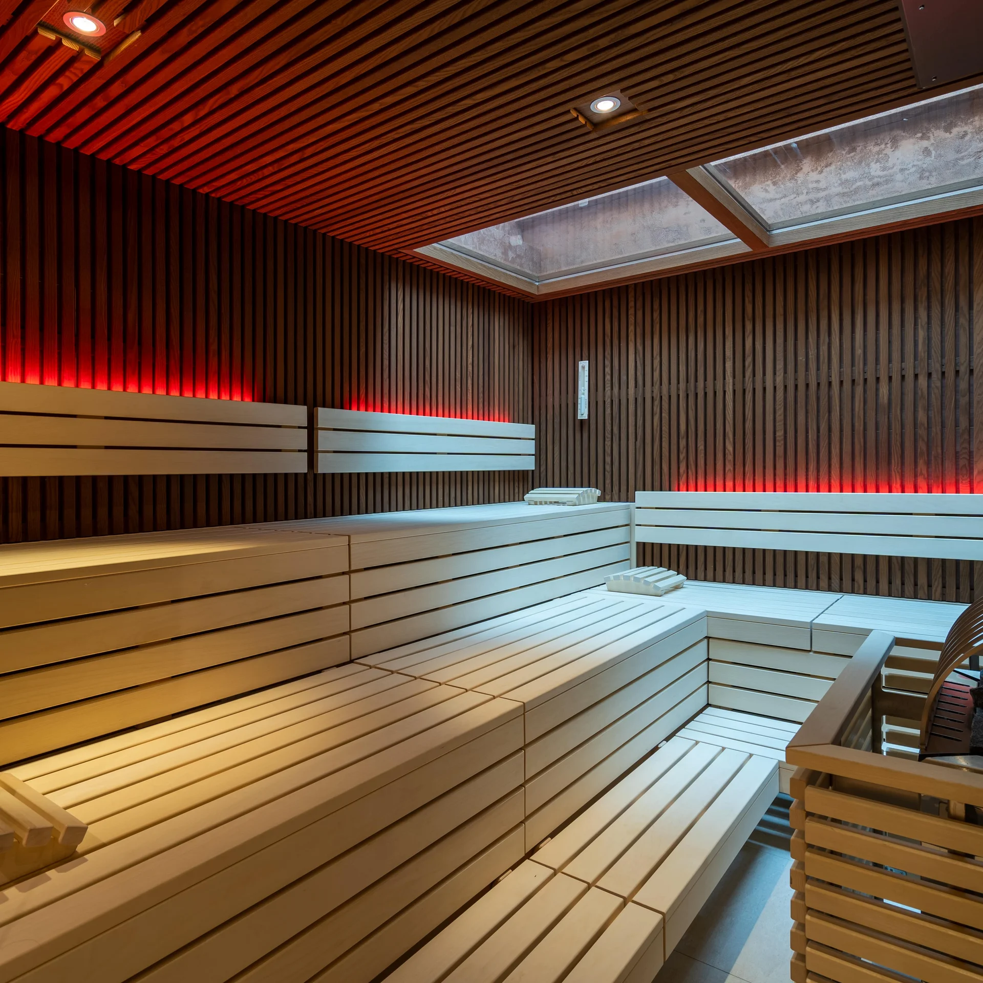 Finnische Sauna mit Holzbänken und indirekter roter Beleuchtung.