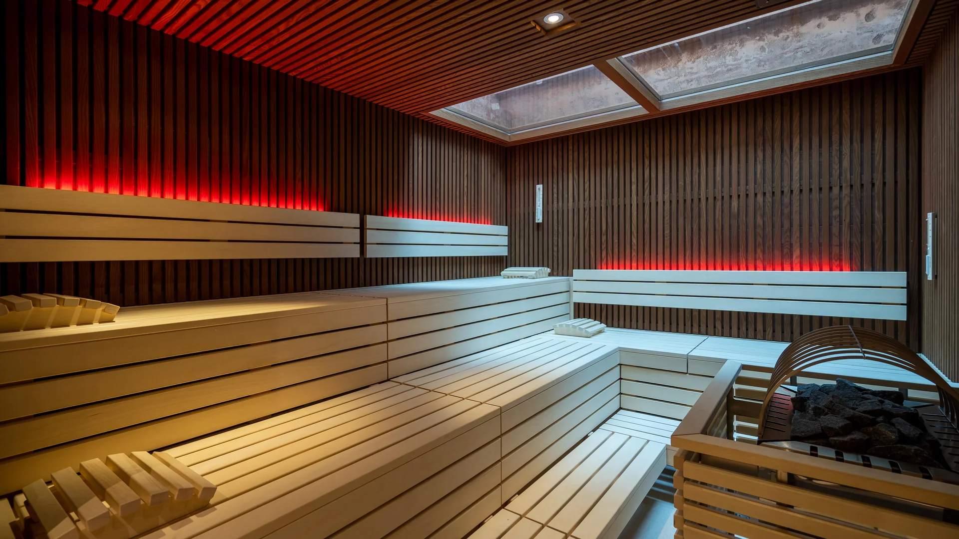 Finnish sauna with wooden benches and indirect red lighting.