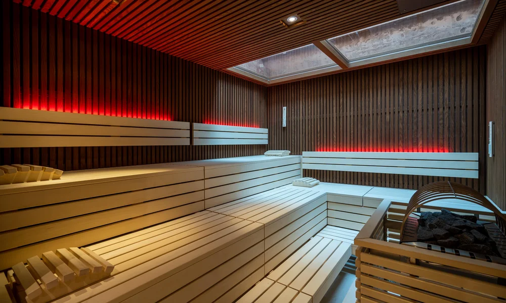 Finnische Sauna mit Holzbänken und indirekter roter Beleuchtung.