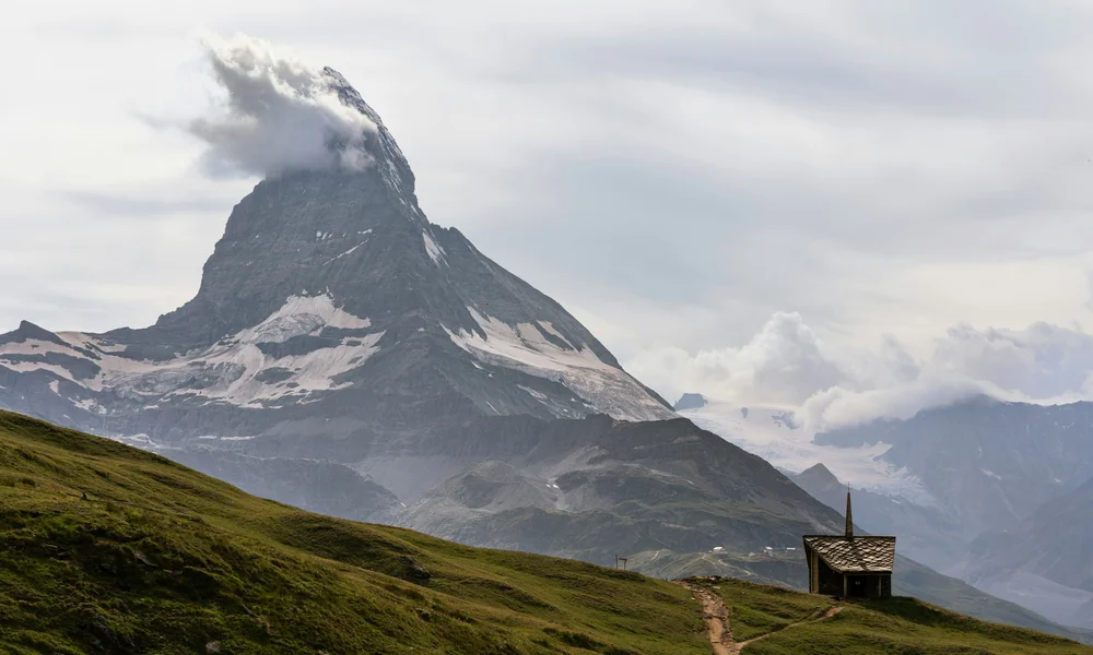 Wandern in Zermatt - Resort La Ginabelle Zermatt Matterhorn mit Wolken und kleine Kapelle auf grünem Hügel