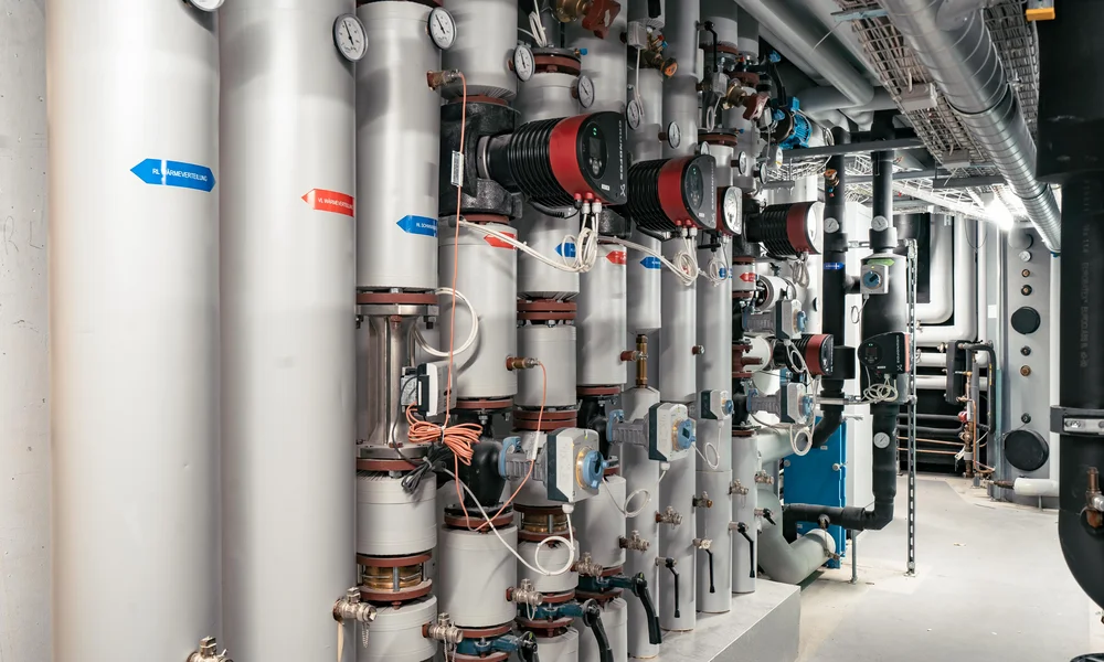 Our energy - Resort La Ginabelle Zermatt Heating pipes and pumps in a technical room.