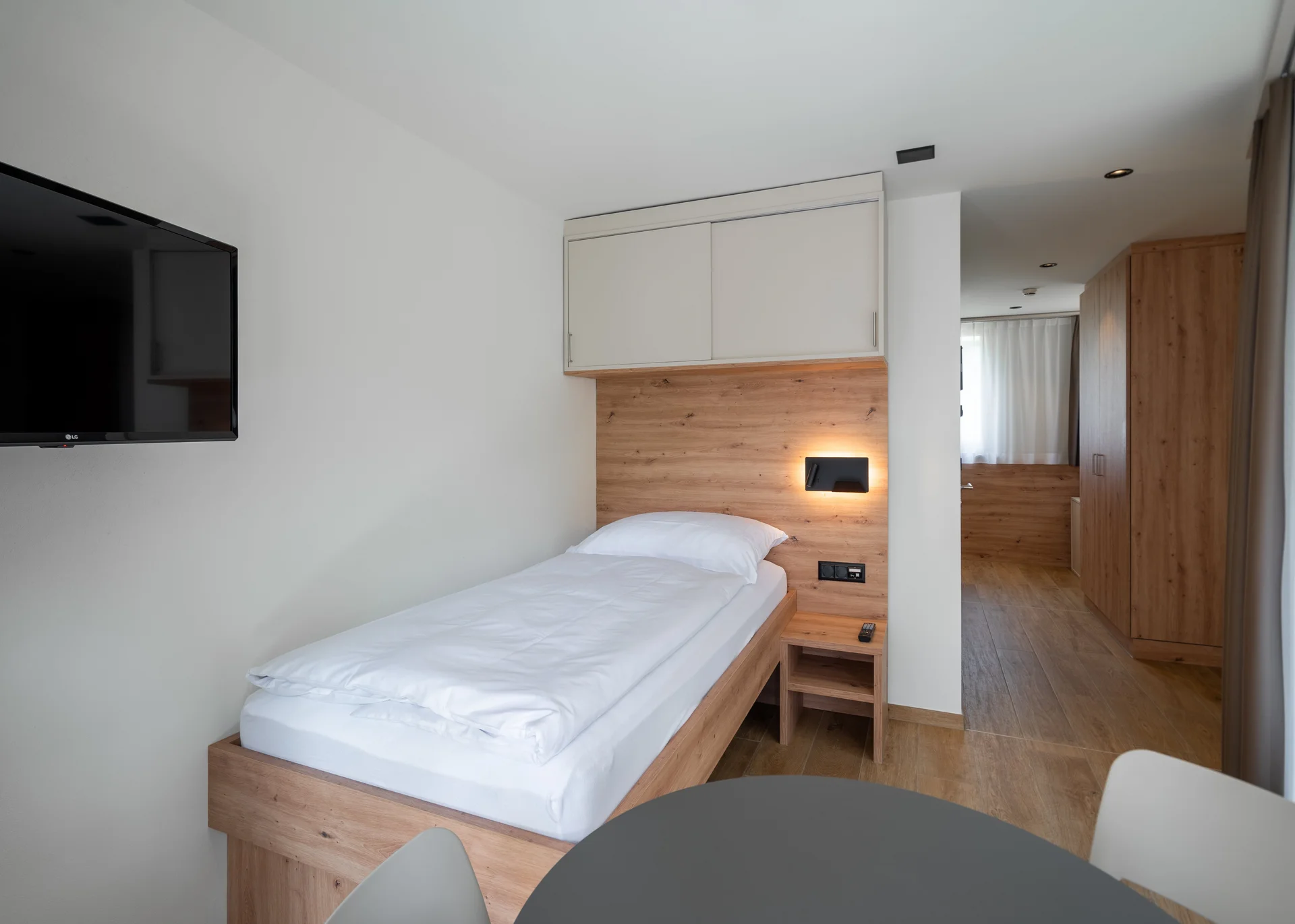 Modernes Studio eingerichtet mit Fernseh, Bett und Schrank.