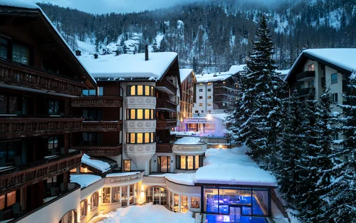 Wintersport Verschneites Hotel mit beleuchtetem Pool und Lichtern in den Fenstern nachts