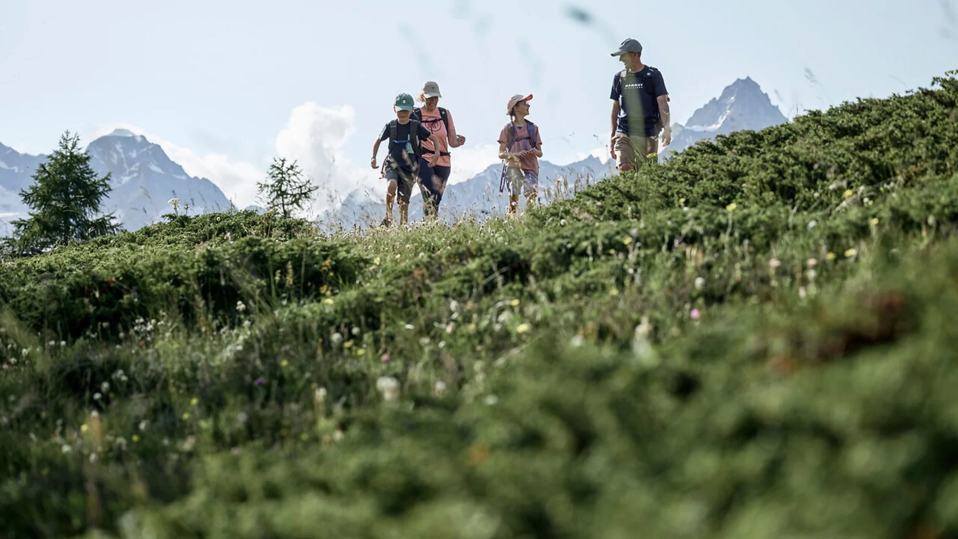 Family hiking on a green hill with mountains in the background