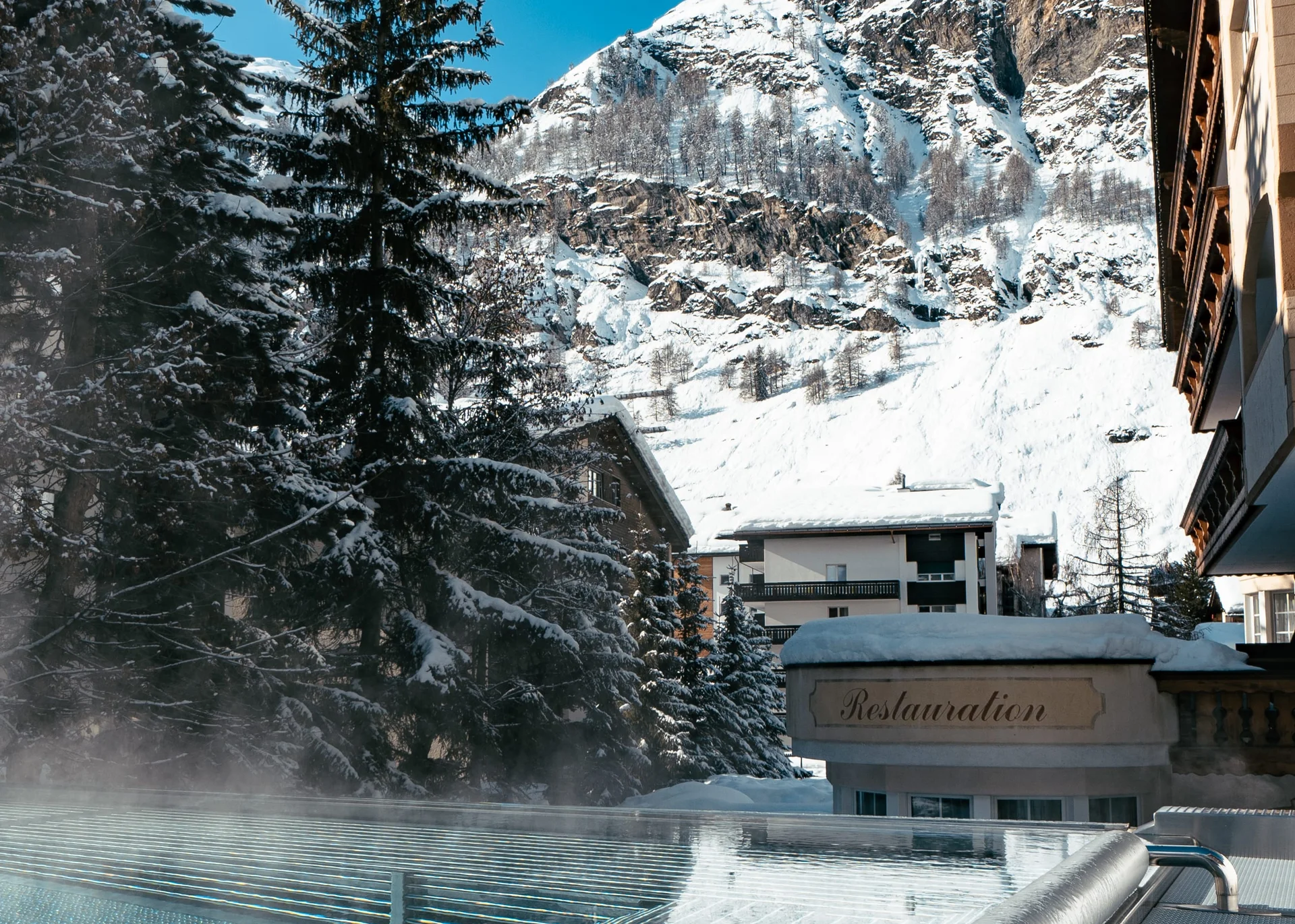 Infinitypool mit Massagedüsen und Aussicht auf die verschneiten Berge im Winter.