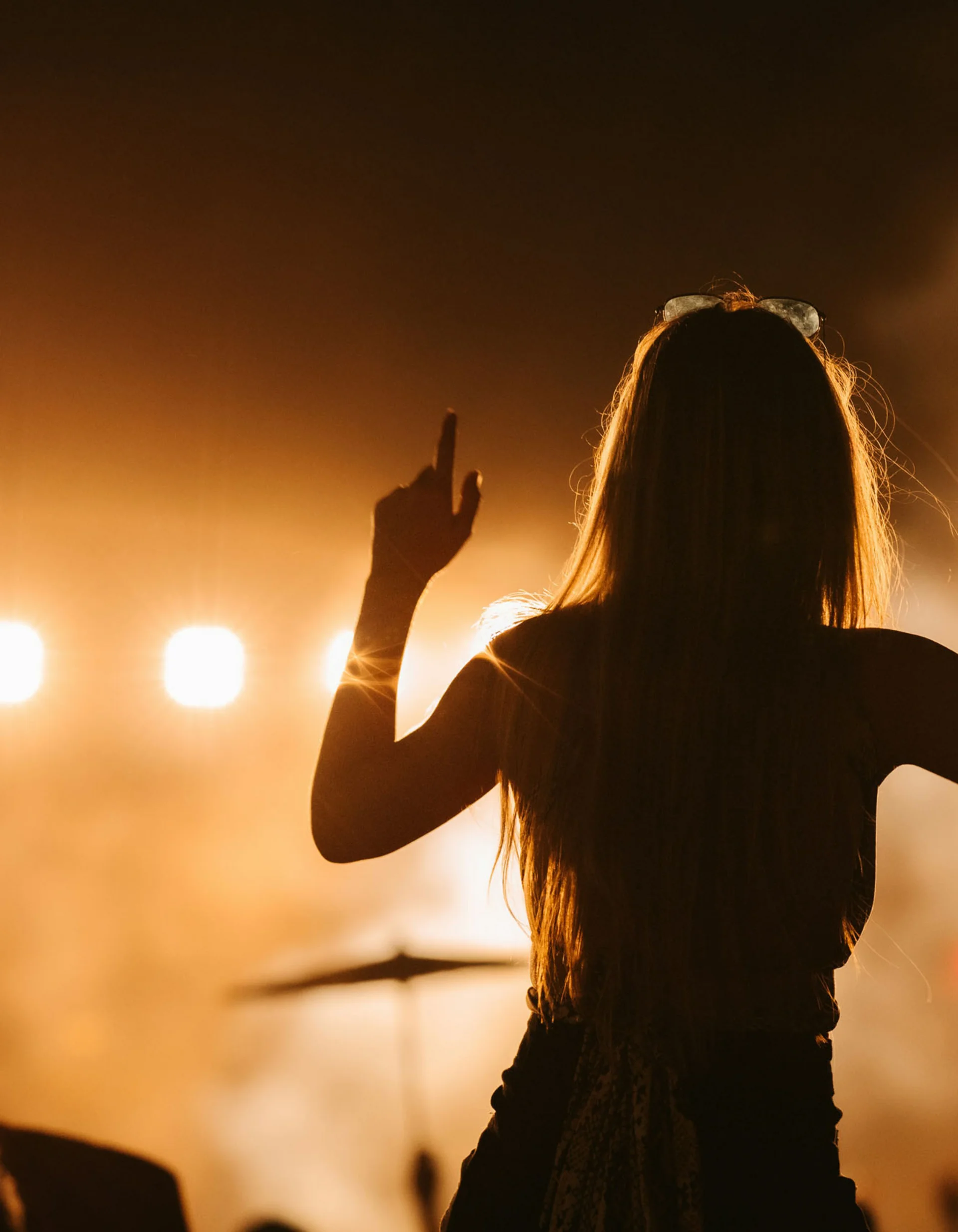Silhouette of a woman in front of stage lights at a concert
