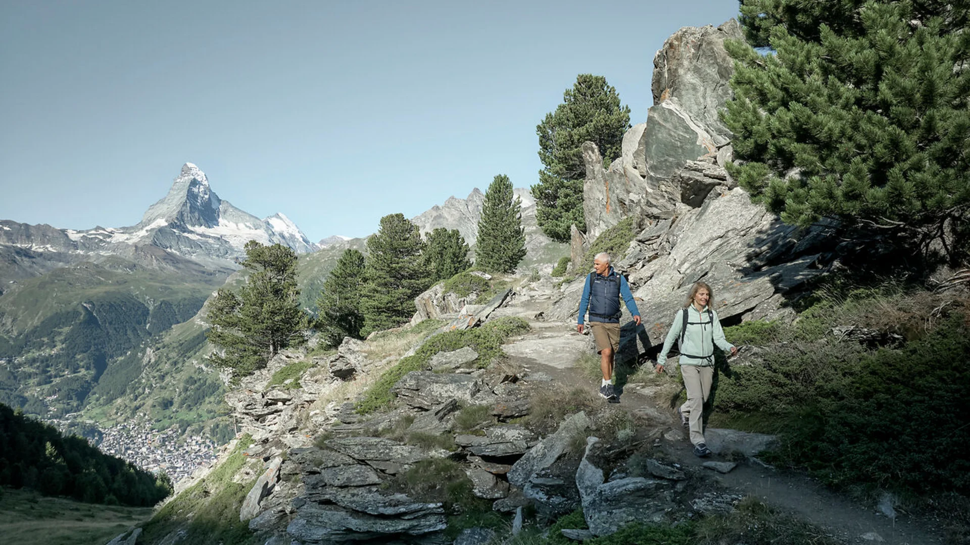 Wandern in Zermatt - Resort La Ginabelle Zermatt Zwei Wanderer auf Bergpfad mit Blick auf Matterhorn und Tannenbäume