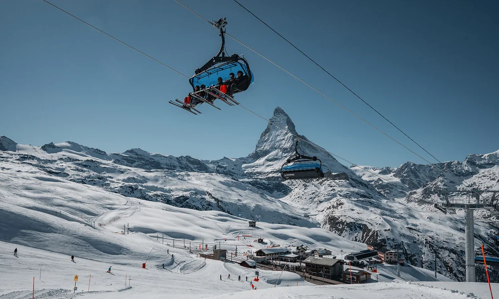 Wintersport Skilift mit Skifahrern vor Matterhorn im Schnee bei blauem Himmel