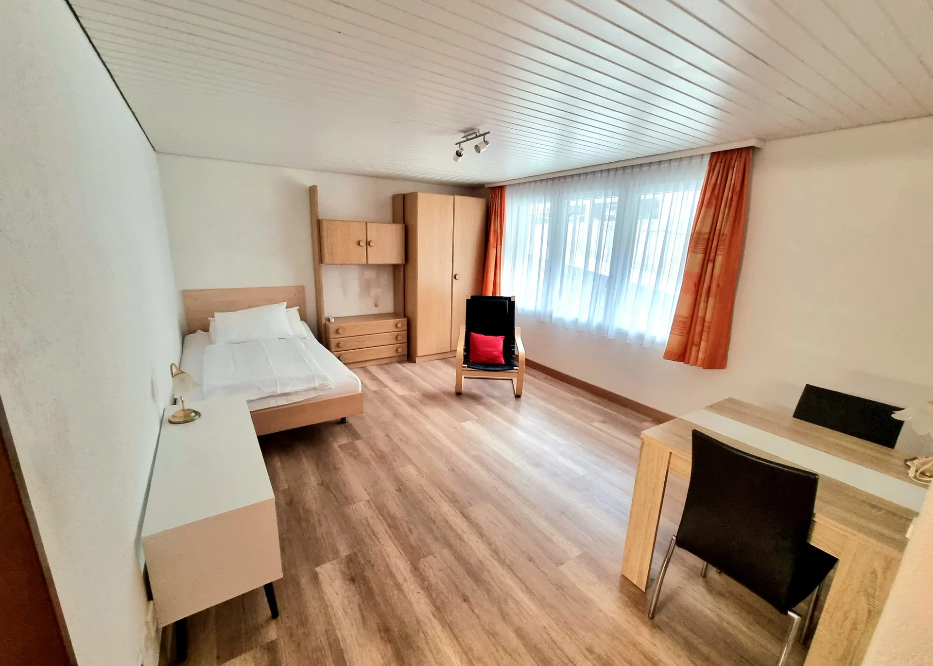 Studio mit Fenter eingerichtet mit Bett, Schrank, Tisch und Stuhl