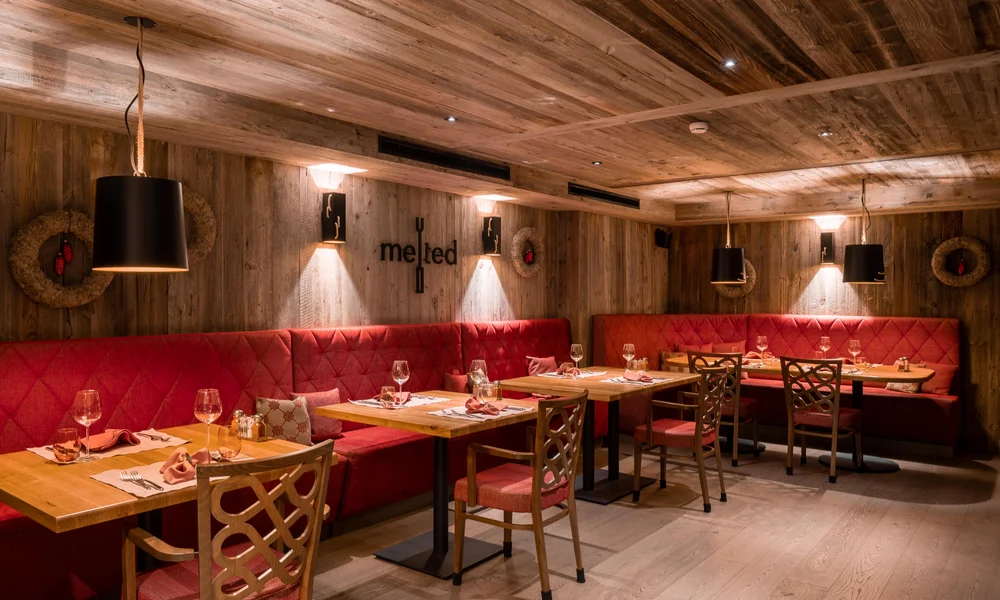 Restaurants at La Ginabelle - Resort La Ginabelle Zermatt Cozy restaurant atmosphere with wood paneling and red upholstery.