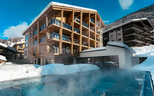 Familienferien in Zermatt - Resort La Ginabelle Zermatt Schneebedecktes Hotel mit Infinitypool