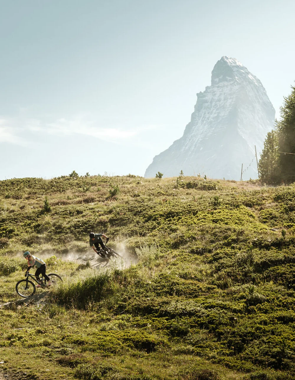 Zwei Mountainbiker fahren auf einem Pfad mit Matterhorn im Hintergrund