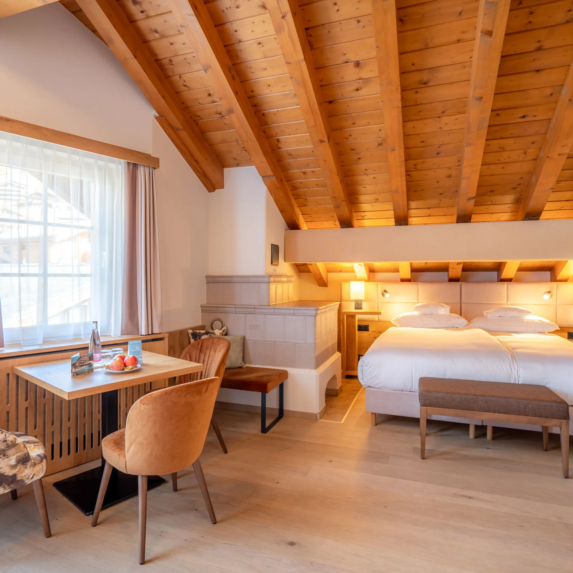 Gemütliches Hotelzimmer mit Holzdecke, Doppelbett und kleinem Tisch am Fenster