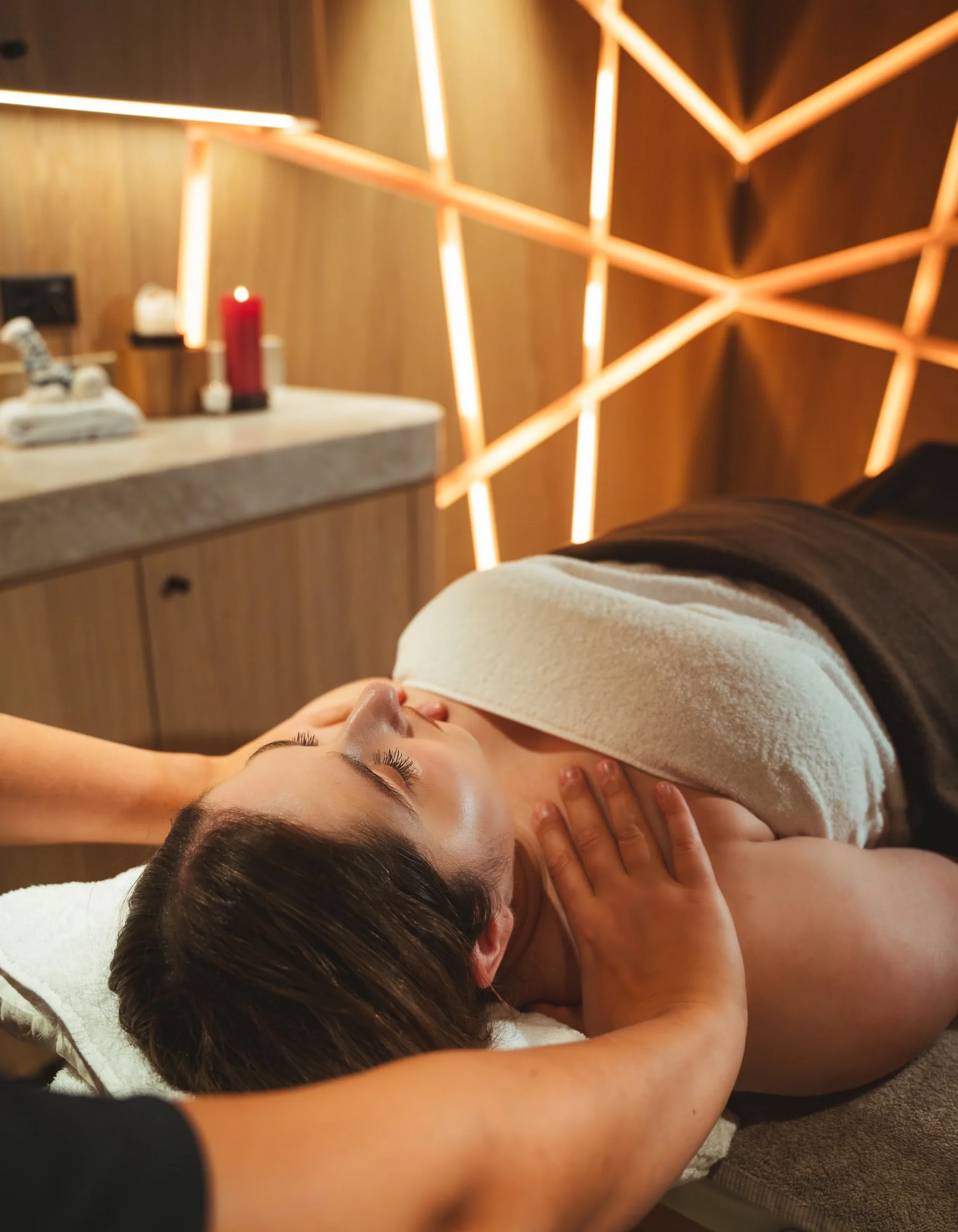 Beauty Treatments & Massages - Resort La Ginabelle Zermatt Neck massage on a woman in a treatment room with illuminated wall paneling.