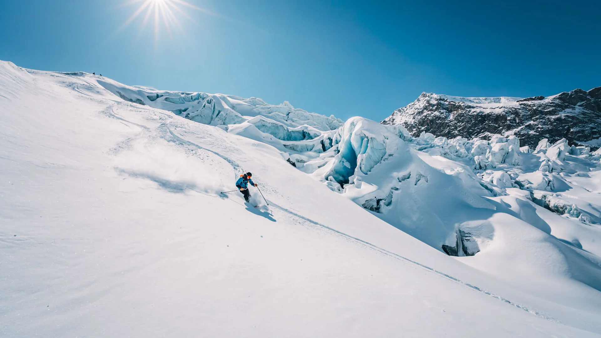 Wintersport Skifahrer fährt bei sonnigem Wetter einen verschneiten Berg hinab