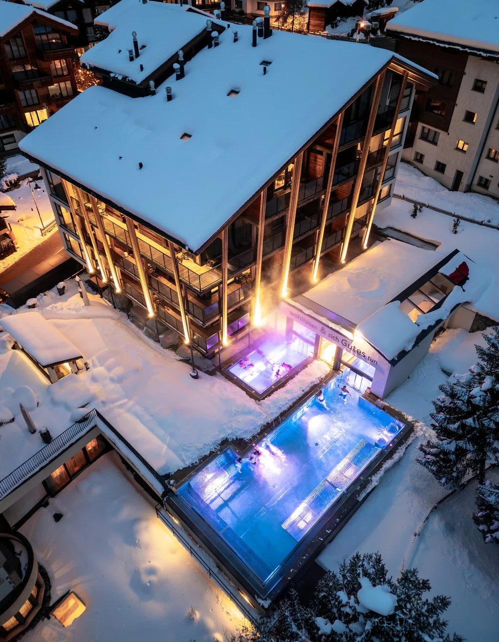 Ferienwohnungen Hotelservice - Resort La Ginabelle Zermatt Schneebedecktes Gebäude mit zwei beheizten Aussenpools.