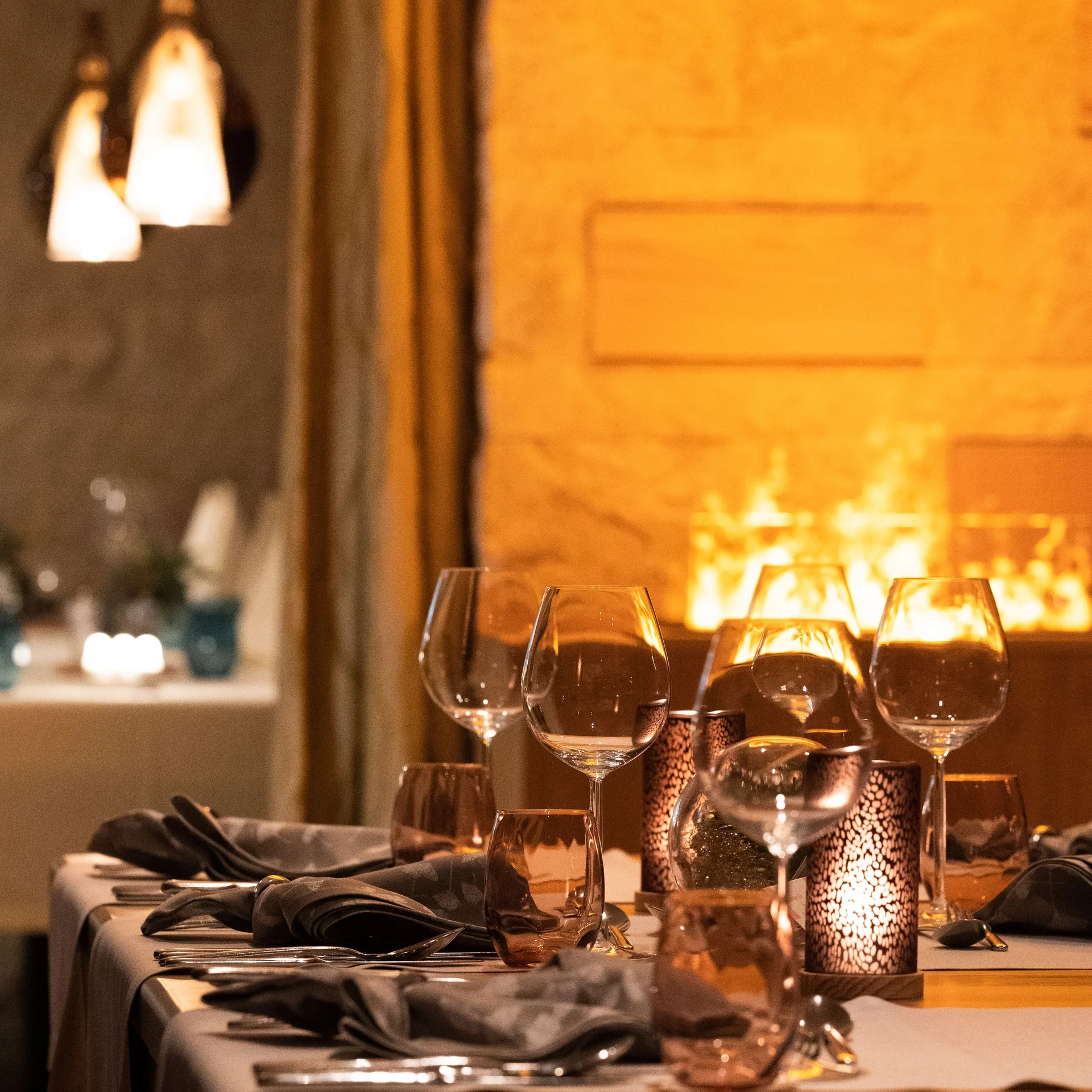 Gedeckte Tische im Restaurant mit stimmungsvollem Kamin im Hintergrund