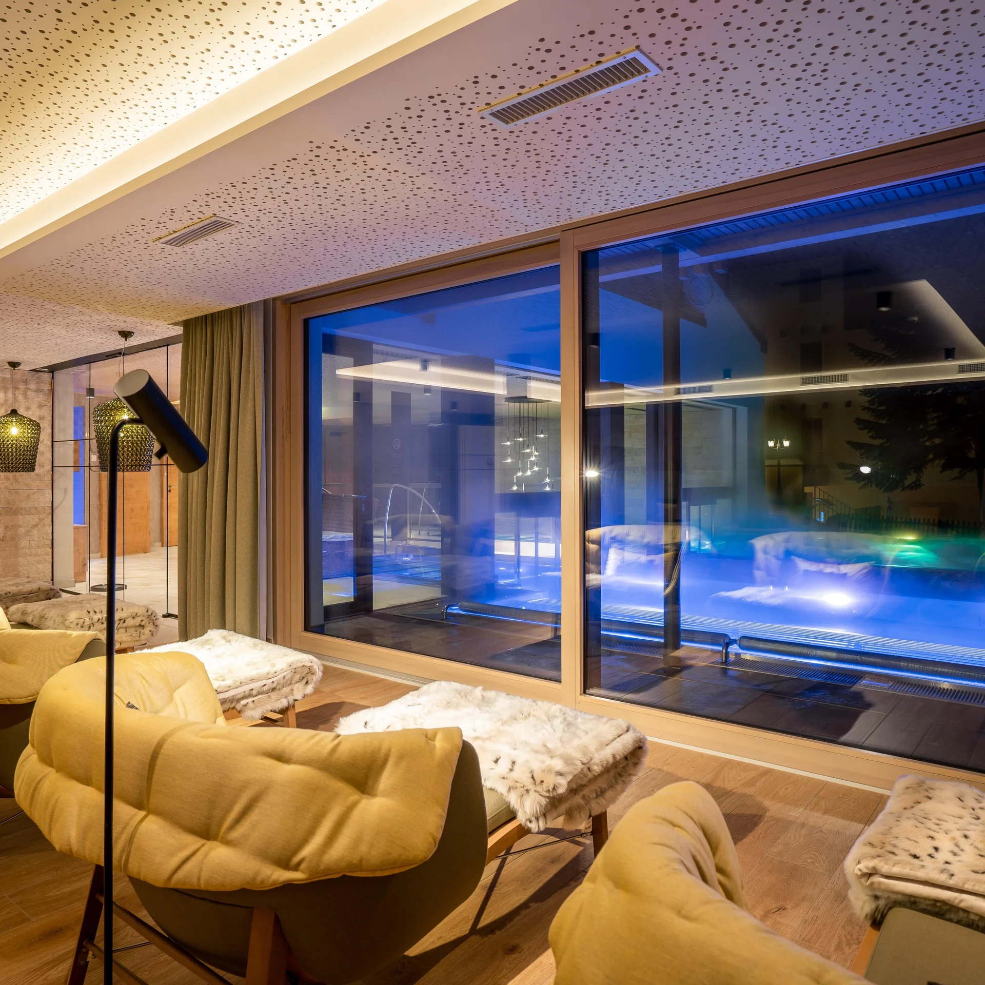 Stimmungsvoller Ruheraum mit Liegen und Kuscheldecke mit Aussicht auf den Aussenpool.