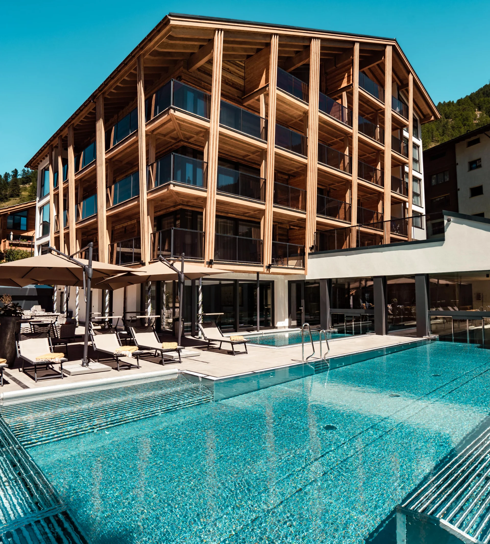 Resort de Bien-Être à Zermatt - Resort La Ginabelle Zermatt Hôtel avec piscine à débordement et terrasse en été.