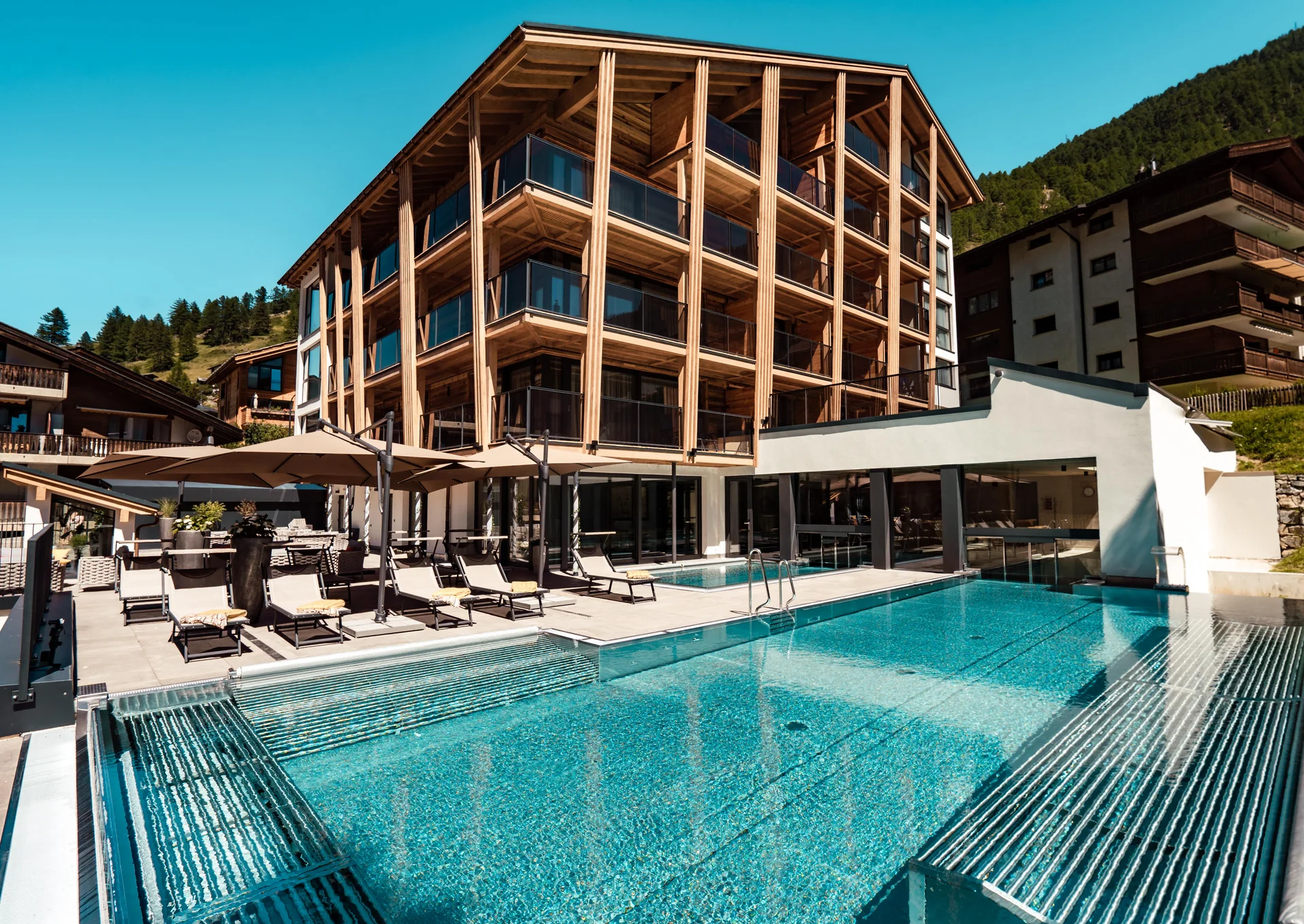 Käsestube melted - Resort La Ginabelle Zermatt Hotel mit Infinitypool und Terrasse im Sommer.