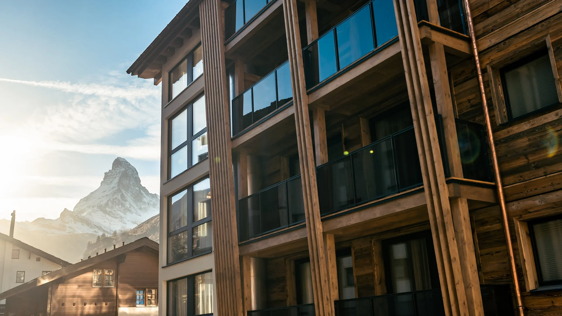 Appartements à Zermatt - Resort La Ginabelle Zermatt Façade d'hôtel avec le Cervin et le coucher de soleil en arrière-plan.