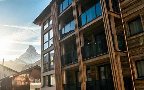 Façade d'hôtel avec le Cervin et le coucher de soleil en arrière-plan.