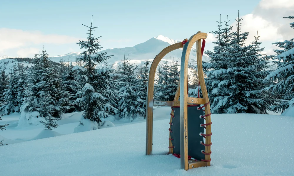 Familienferien in Zermatt - Resort La Ginabelle Zermatt Schlitten steht im Schnee vor verschneiten Tannen und Bergen