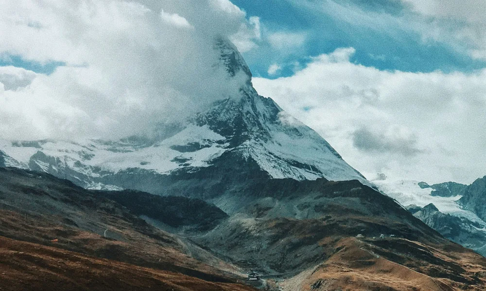 Wandern & Bergsteigen Zermatt - Resort La Ginabelle Zermatt Schneebedeckter Berg teilweise von Wolken verdeckt über braunen Hügeln