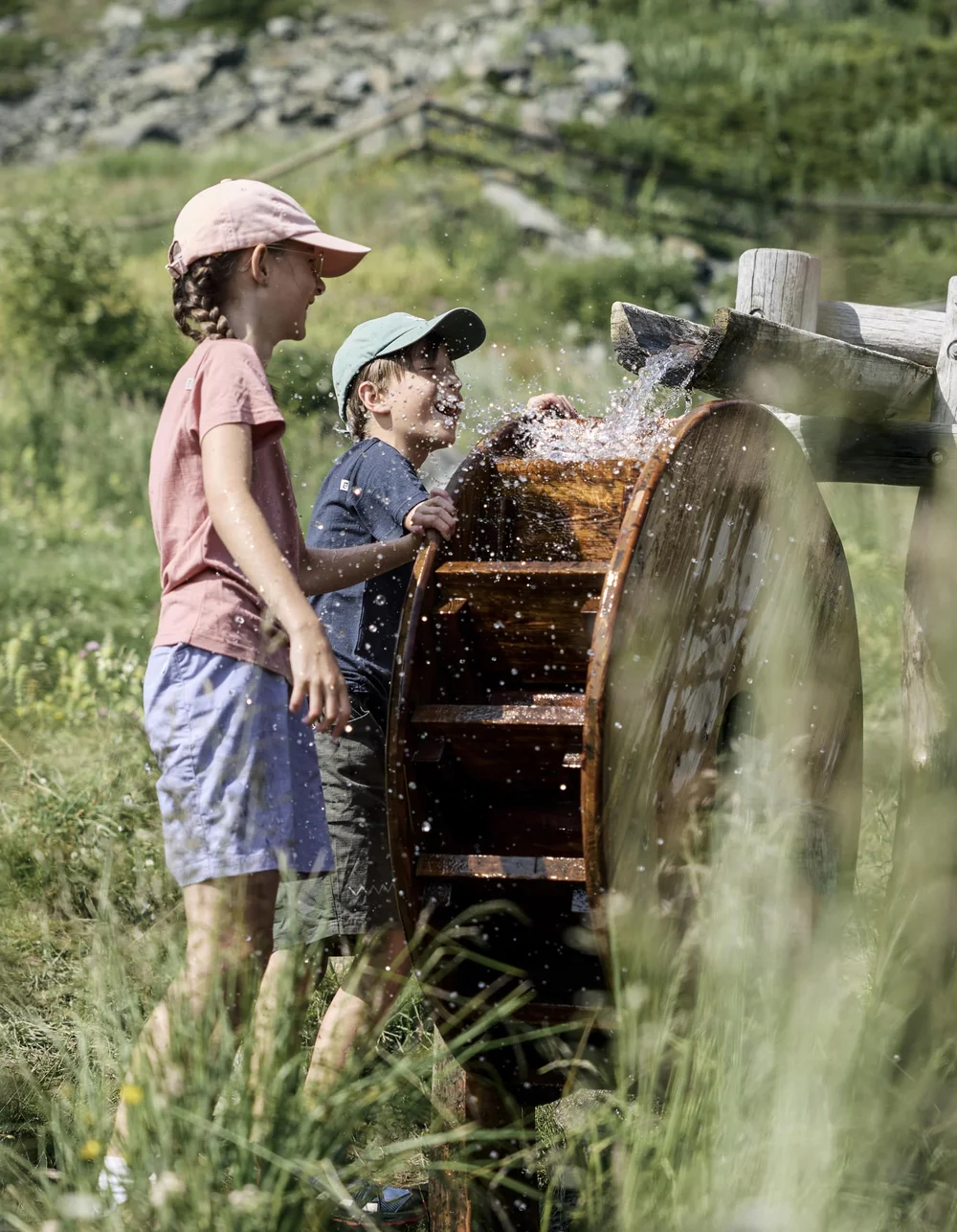 Kinder spielen im Sommer an einem Wasserspielplatz.